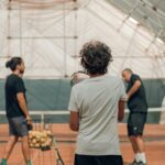 Un groupe de personnes s'entraine avec un coach de tennis