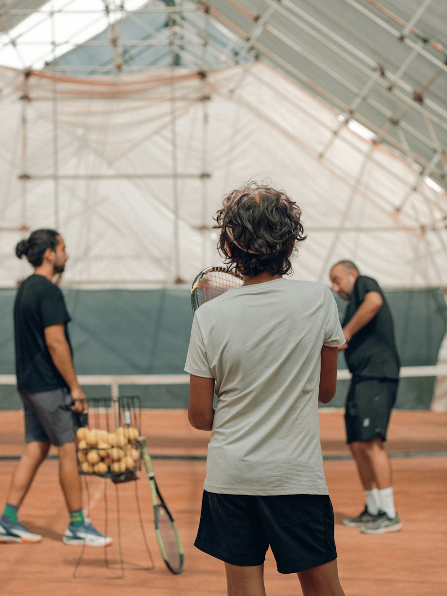 Un groupe de personnes s'entraine avec un coach de tennis