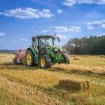 tracteur vert sur un champ d'herbe brune sous un ciel bleu pendant la journée